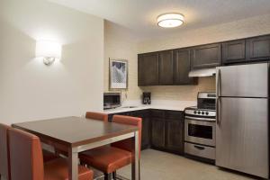 a kitchen with a table and a stainless steel refrigerator at Residence Inn Detroit / Auburn Hills in Pontiac