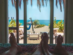 una persona tumbada en una cama mirando por una ventana en la playa en Palo Santo Sanctuary, en Canoas de Punta Sal