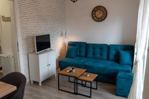 uma sala de estar com um sofá azul e uma televisão em Lux Apartment III Prijedor em Prijedor