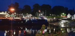 a group of boats docked in a harbor at night at Cosy apartment in popular harbour town in Kirkcudbright