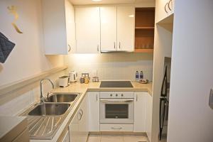 a small kitchen with white cabinets and a sink at Luna Breeze - Elegant 2BR Apartment with Beach Access, Near Al Raha Beach in Abu Dhabi