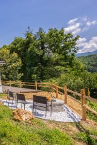 a patio with two chairs and a table next to a fence at STEPS TO BRYSON - MTN VIEWS, HOT TUB, FIREPIT, WALK TO TOWN! in Bryson City