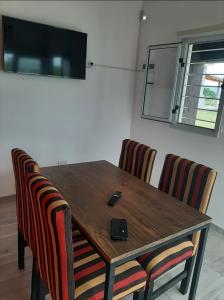 a wooden table with two chairs with a remote control on it at Altos apparts in Estancia Vieja