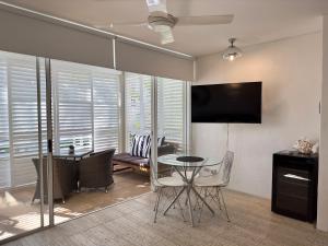 a dining room with a table and chairs and a television at Oasis Rooftop Spa Apartment in Noosa Heads