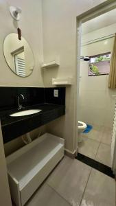a bathroom with a sink and a mirror and a toilet at Área vip maranduba in Ubatuba