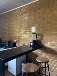 a kitchen with a counter and two stools in front of a brick wall at Lar do sertão- flat dentro do Hotel Fazenda Pedra do Rodeadouro in Bonito