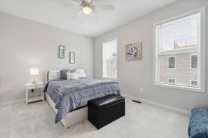 a white bedroom with a bed and two windows at Spacious 3Bedroom Duplex with Rooftop Deck! in Washington, D.C.