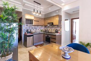 a kitchen with a wooden table and a dining room at Bel appartement moderne au cœur de guelize in Marrakesh