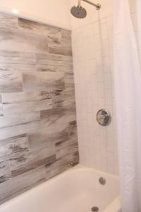 ein Badezimmer mit einer Dusche und einer weißen Badewanne in der Unterkunft Elegant 3Br Apt Yankee stadium in Melrose