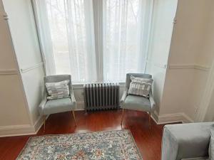 2 Stühle und ein Heizkörper in einem Zimmer mit Fenster in der Unterkunft Elegant 3Br Apt Yankee stadium in Melrose