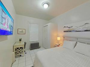 1 Schlafzimmer mit einem weißen Bett und einem TV in der Unterkunft Elegant 3Br Apt Yankee stadium in Melrose