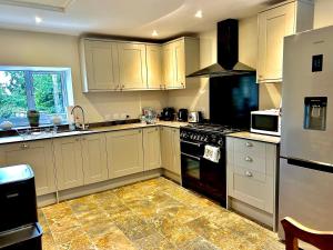 cocina con armarios blancos y fogones en Springbank Cottage, en Stroud