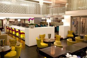 ein Restaurant mit gelben Stühlen und Tischen und eine Bar in der Unterkunft DoubleTree by Hilton Cape Town Upper Eastside in Kapstadt
