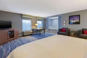 a hotel room with a bed and a flat screen tv at Hampton Inn Cincinnati Airport-North in Hebron