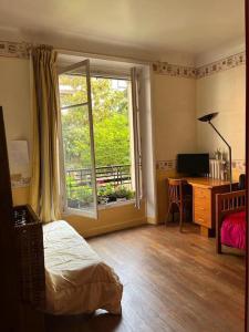 a bedroom with a bed and a window and a desk at Le grand calme à deux pas de Paris in Neuilly-sur-Seine