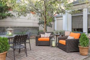 a patio with wicker chairs and a table with an orange pillow at Hilton Garden Inn Tallahassee in Tallahassee