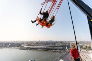 two people on a swing on the top of a building at Hilton Amsterdam Airport Schiphol in Schiphol