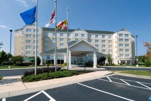 ein Hotel mit Flaggen vor einem Parkplatz in der Unterkunft Hilton Garden Inn Owings Mills in Owings Mills