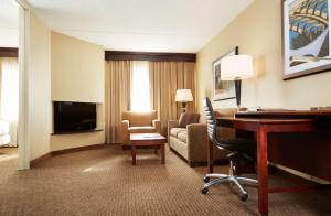 DoubleTree Suites by Hilton Hotel Cincinnati - Blue Ash في شارونفيل: غرفة في الفندق مع مكتب وغرفة معيشة