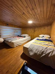 Habitación con 2 camas, paredes de madera y suelo de madera. en Havuzlu kiralık Tinyhause, en Çekme