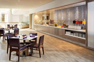 a restaurant with tables and chairs and a counter at Hilton Long Beach Hotel in Long Beach