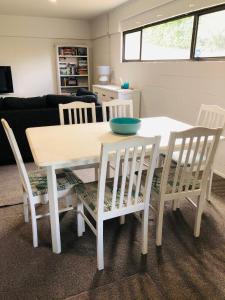 een witte eettafel met 4 stoelen en een tafel bij Waikaraka Beach, spacious & very comfortable in Whangarei Heads