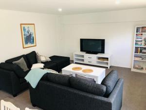 a living room with two couches and a flat screen tv at Waikaraka Beach, spacious & very comfortable in Whangarei Heads