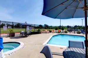 a swimming pool with an umbrella and tables and chairs at Hampton Inn Houston I-10 East, TX in Houston