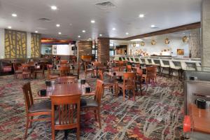 a restaurant with wooden tables and chairs and a bar at DoubleTree by Hilton Lawrence in Lawrence