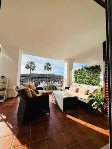 sala de estar con 2 sofás y balcón con palmeras en Feel The Vibe Alcaidesa en San Roque