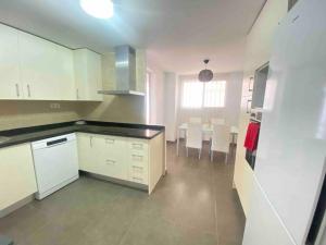 a kitchen with white cabinets and a table and chairs at Feel The Vibe Alcaidesa in San Roque