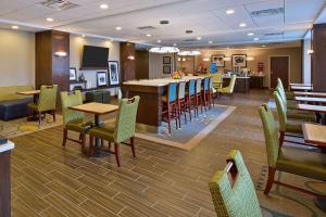 a restaurant with tables and chairs and a bar at Hampton Inn Southfield/West Bloomfield in Farmington Hills