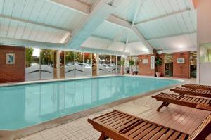 - une grande piscine avec bancs dans un bâtiment dans l'établissement DoubleTree by Hilton Newbury North, à Newbury