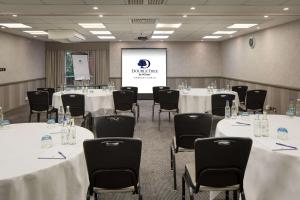 a conference room with tables and chairs and a screen at DoubleTree by Hilton Newbury North in Newbury