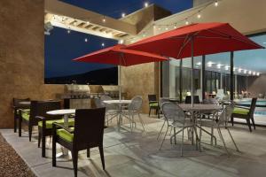 Home2 Suites By Hilton Richland في ريتشلاند: مطعم فيه طاولات وكراسي فيه مظلات حمراء