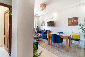 een woonkamer met een tafel en blauwe stoelen bij Bel appartement moderne au cœur de guelize in Marrakesh