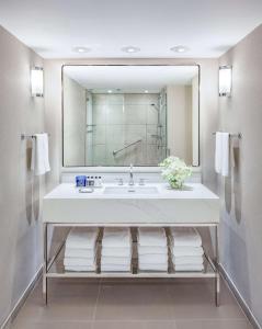 a bathroom with a sink and a large mirror at The Marquette Hotel, Curio Collection by Hilton in Minneapolis