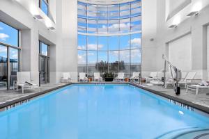 una piscina con agua azul en un edificio con ventanas en Embassy Suites by Hilton Houston West - Katy en Houston