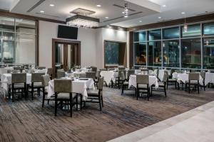 a restaurant with white tables and chairs and windows at Embassy Suites by Hilton Houston West - Katy in Houston