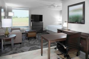 a hotel room with a bedroom with a bed and a desk at Homewood Suites By Hilton Lansing Eastwood in Lansing