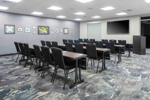 une salle de conférence avec des tables, des chaises et un écran dans l'établissement Homewood Suites By Hilton Lansing Eastwood, à Lansing