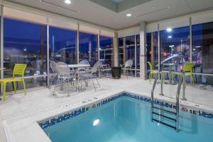 a swimming pool with chairs and a table on a building at Home2 Suites Kansas City Downtown in Kansas City