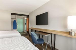 ウィチタにあるTru By Hilton Wichita Northeastのベッド、デスク、テレビが備わるホテルルームです。