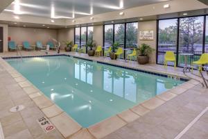 a large swimming pool in a hotel lobby with yellow chairs at Home2 Suites By Hilton Fort Collins in Fort Collins