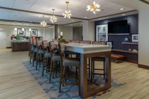 a bar with stools in a large room with a restaurant at Hampton Inn Bourbonnais Kankakee in Bourbonnais