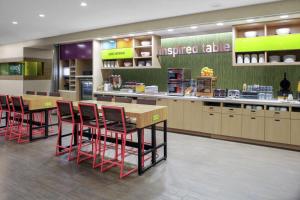 a kitchen with tables and chairs in a restaurant at Home2 Suites By Hilton Fort Collins in Fort Collins