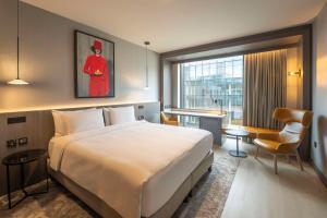 a hotel room with a large bed and a chair at Radisson Blu Royal Hotel Dublin in Dublin
