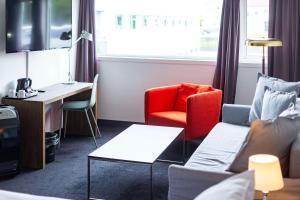 une chambre d'hôtel avec un bureau, un canapé et une chaise dans l'établissement Park Inn by Radisson Haugesund Airport, à Avaldsnes