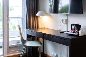 Habitación con ventana y escritorio con silla. en Park Inn by Radisson Haugesund Airport en Avaldsnes