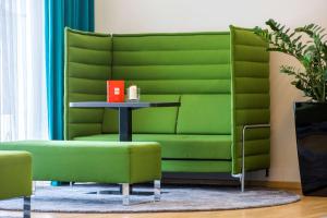 ein grünes Sofa in einem Zimmer mit Tisch in der Unterkunft Park Inn by Radisson Nürnberg in Nürnberg